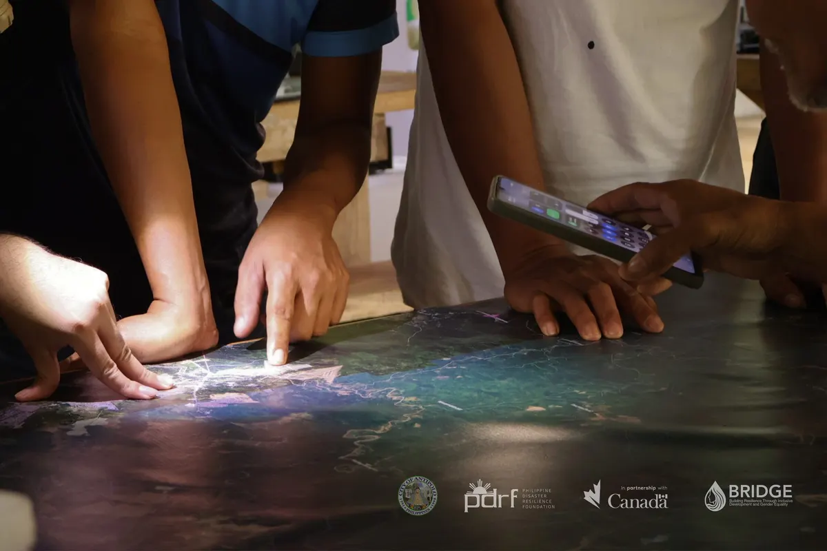 Participants point to locations on an illuminated map during the mapping workshop.